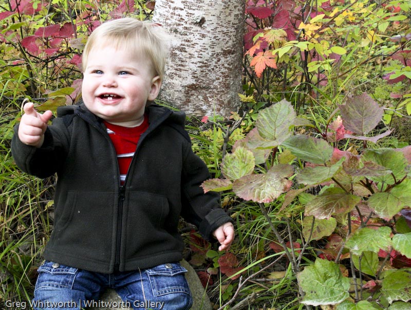 A young Matt smiling beside a tree in autumn